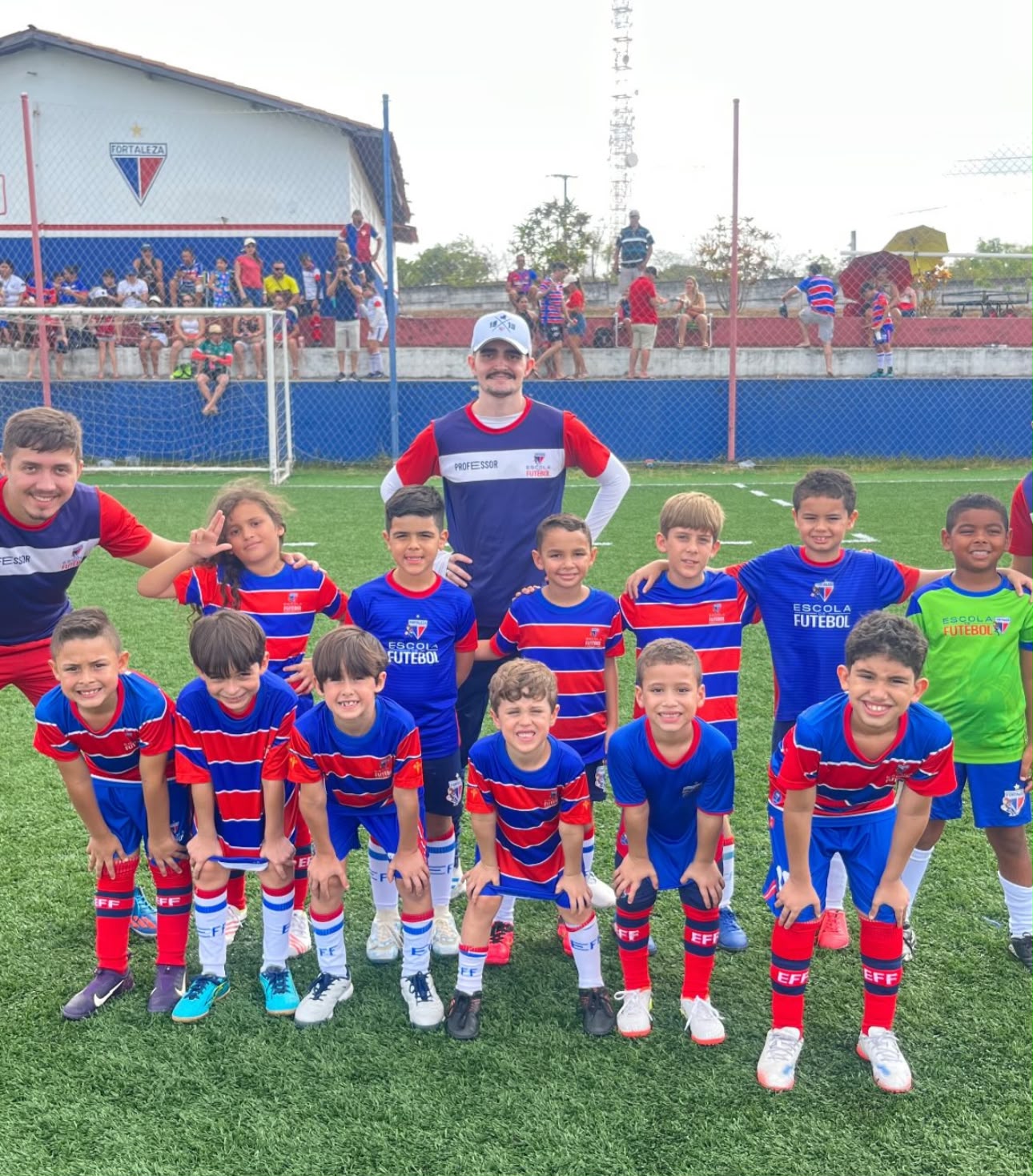 Grupo de alunos e professor sorrindo em campo