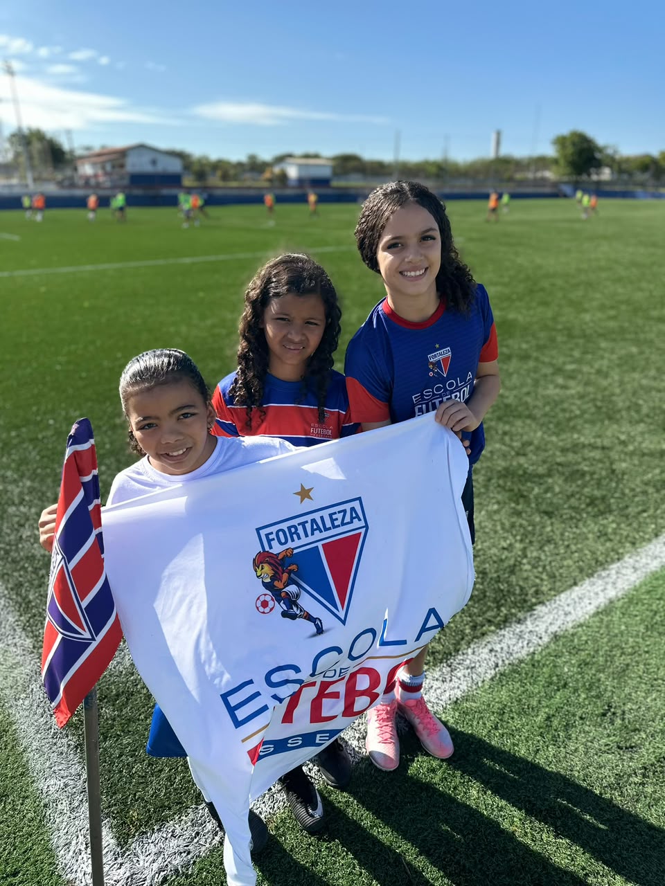 Alunas segurando a bandeira da Escola de Futebol Fortaleza